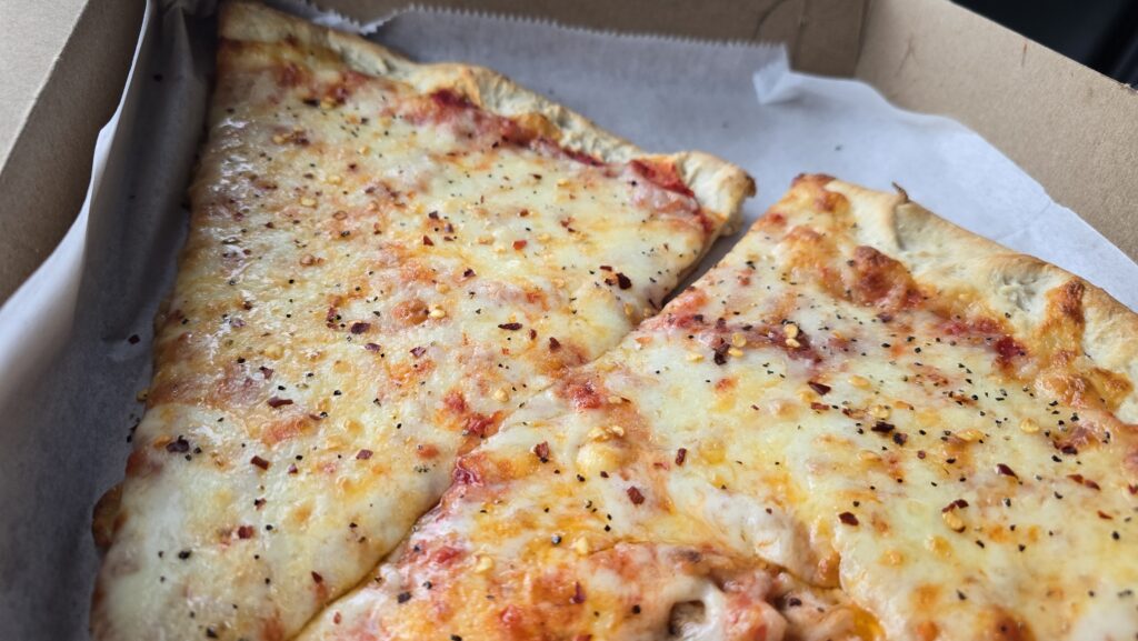 close up picture of 2 slices of pizza at Miseno II Pizzeria & Italian in Carlisle, PA with red pepper flakes and black pepper on them - best slice of pizza in Carlisle Pennsylvania - awesome carlisle - best of carlisle, pa