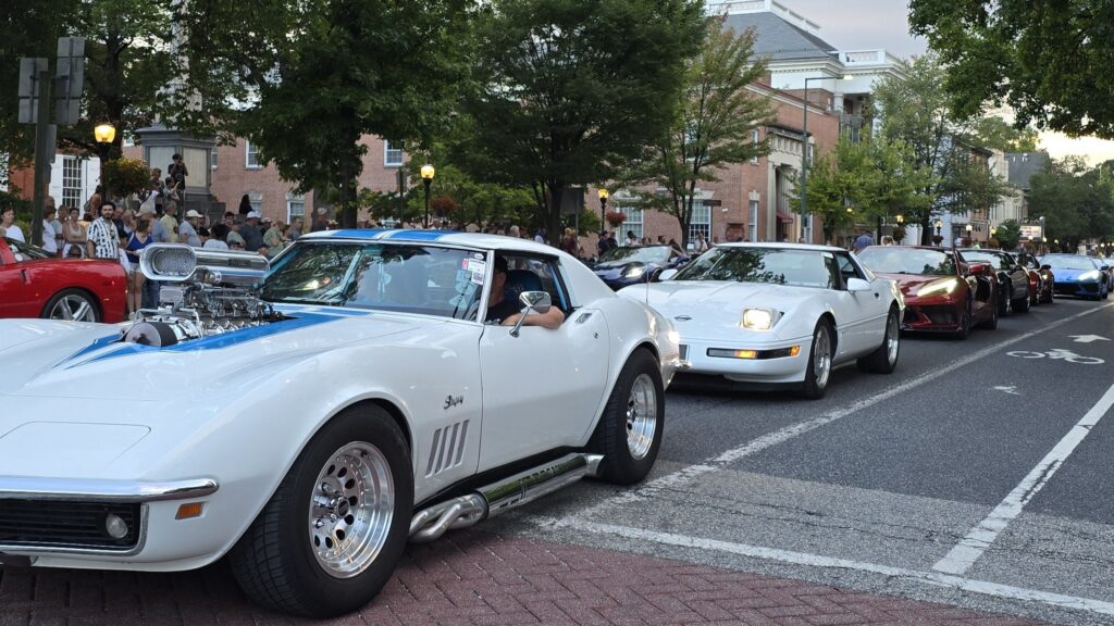 Corner of S Hanover St and W High St in Carlisle, PA during the Corvettes at Carlisle parade on August 29, 2026 showing a couple white corvettes and others behind them - awesome carlisle - carlisle, pa news